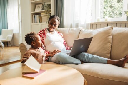 Mother taking care about baby and working on laptop at home