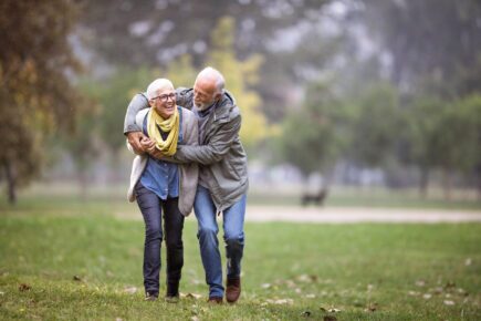 Playful mature couple having fun during rainy day at the park.