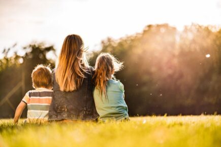 Mother and her children in a field on their own.